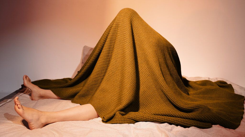Person with a specific phobia hiding under a blanket