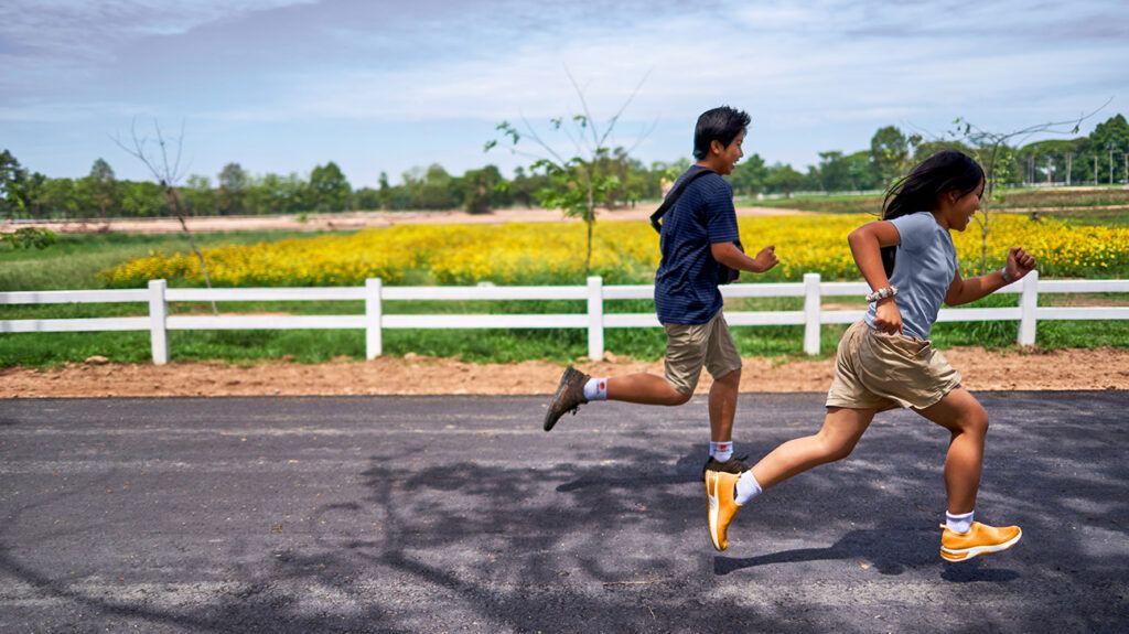 a boy and girl running alongside an empty field