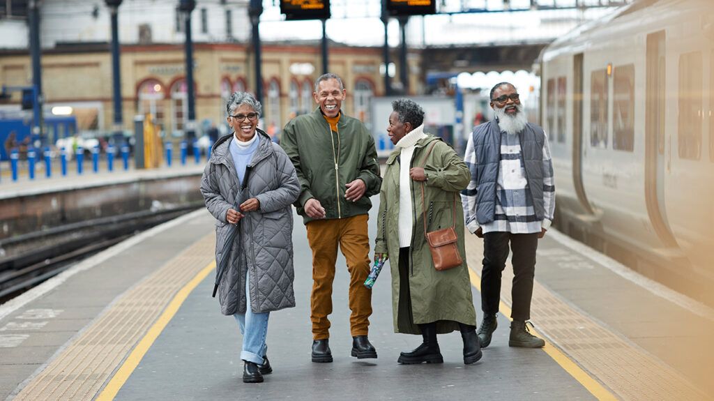 two elderly couples walking in a train station