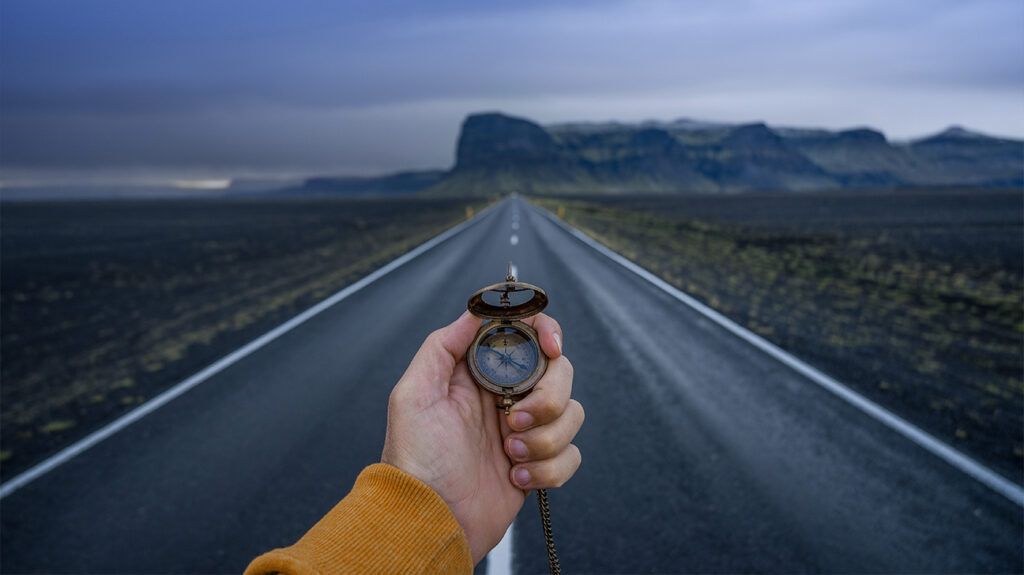person on empty road holding a compass 