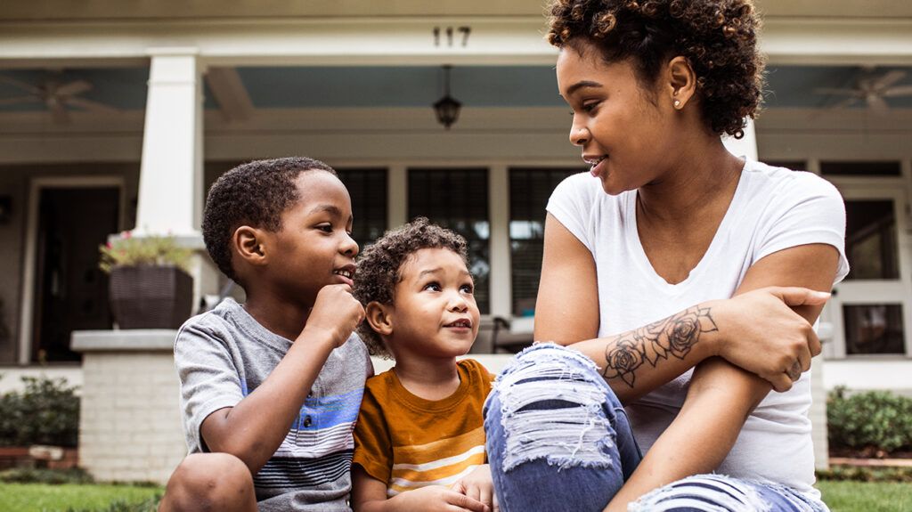 a mother talking to her two young sons outside