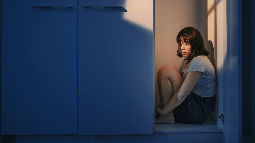 a teen girl sitting in a closet dealing with anxiety emotion