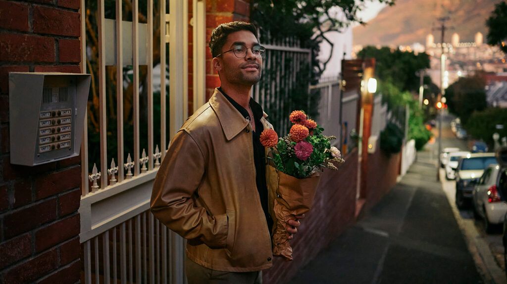 a romantic man waiting outside with a bouquet of flowers
