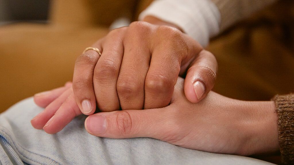 close up of two people holding hands as a supportive gesture