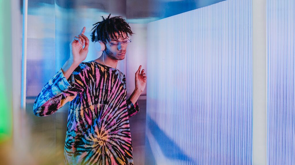 a man dancing with headphones on while surrounded by colorful lights