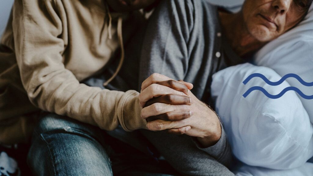 Daughter holding depressed father's hand at home.