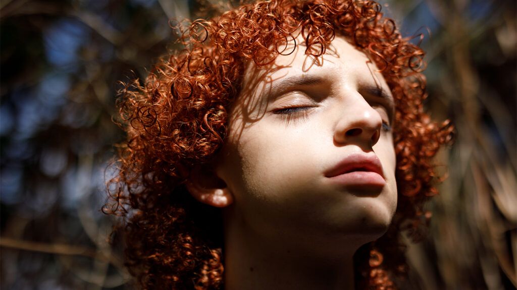 A person with red, curly hair looking anxious