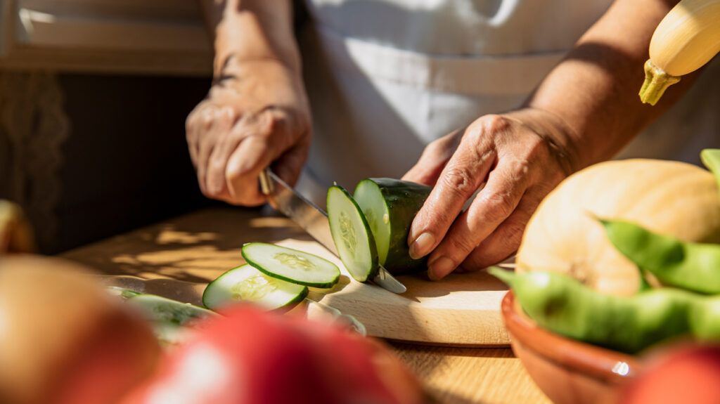 An older person cutting vegetables in the kitchen.