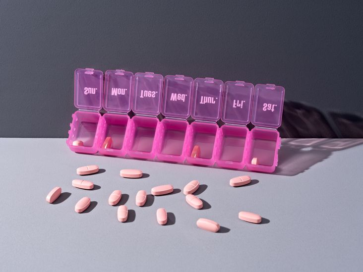 A purple supplement organizer with pills spread across the table