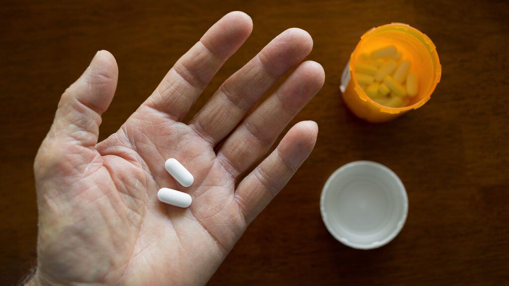 An open hand holding two white pills