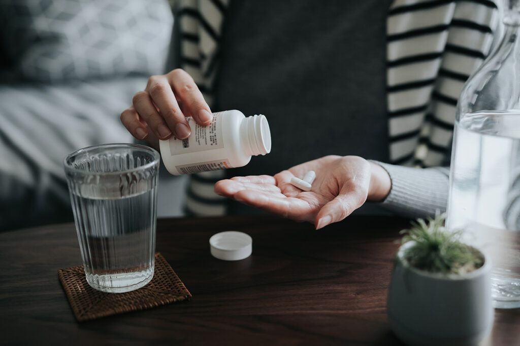 A person dropping a pill from a pill bottle into their hand