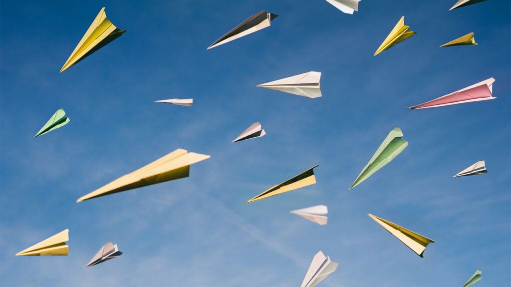 Many different colored paper airplanes flying against a sky backdrop depicting a calmness about aviophobia when looking for flight anxiety medication