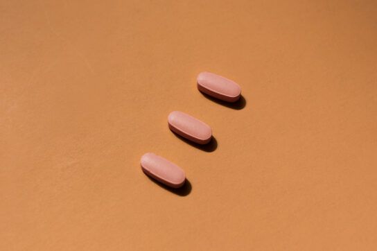 Three pink pills on an orange background