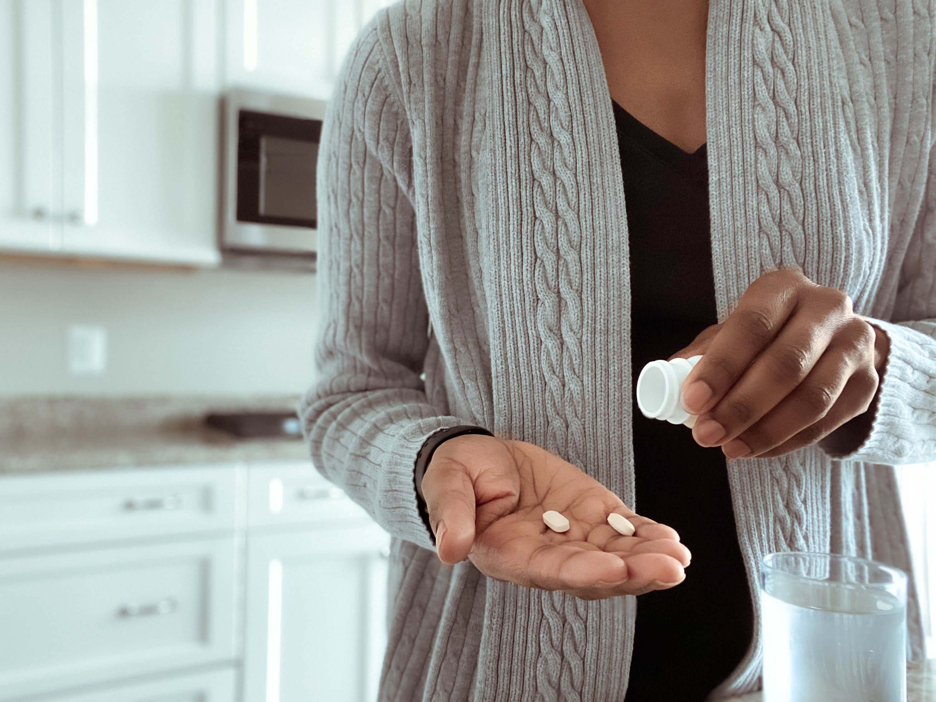 Woman holding pill bottle with two pills in her hand
