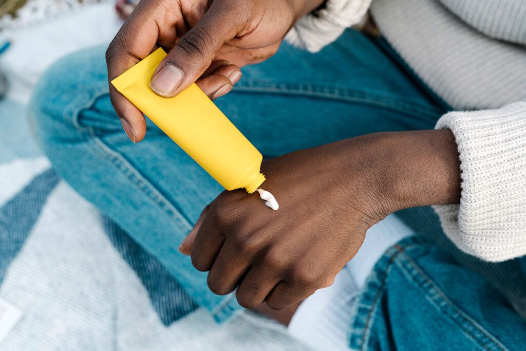 A person applying skin cream to their hand