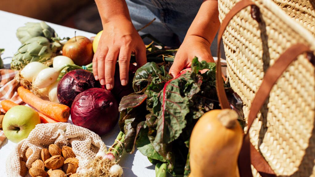 A person standing in front of many fruits and vegetables