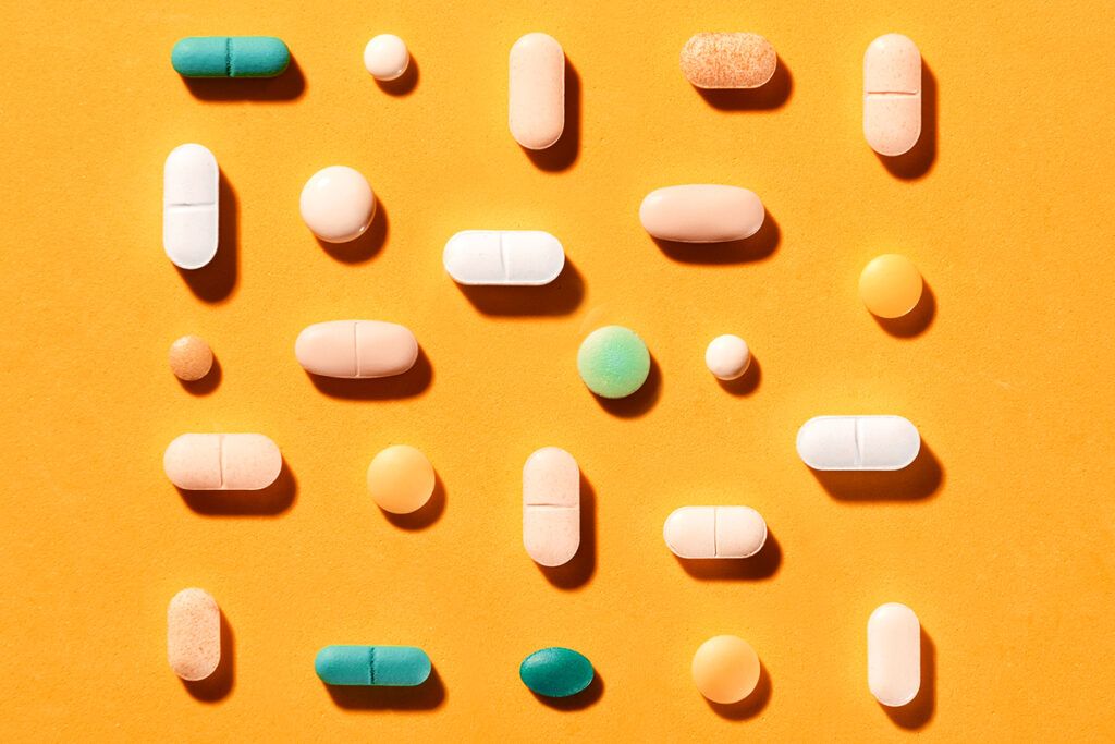 Pills of different colors on orange background
