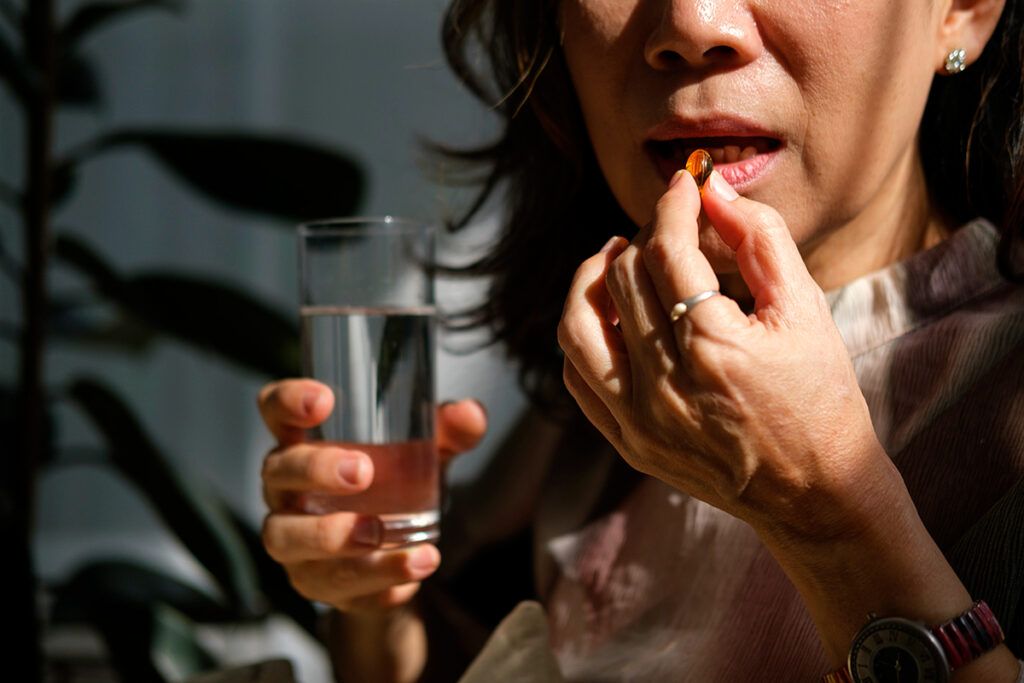 A person taking a pill with a glass of water