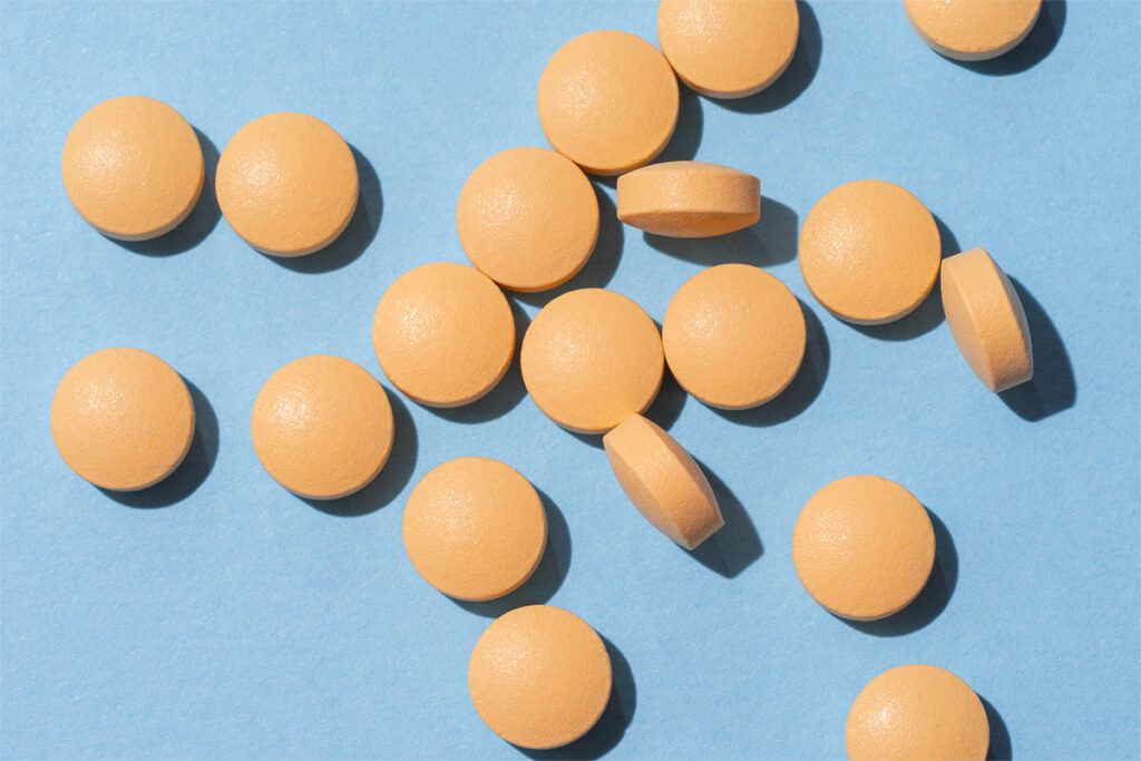 randomly scattered, flat, round, orange pills on a blue background that could be supplements for nerve pain
