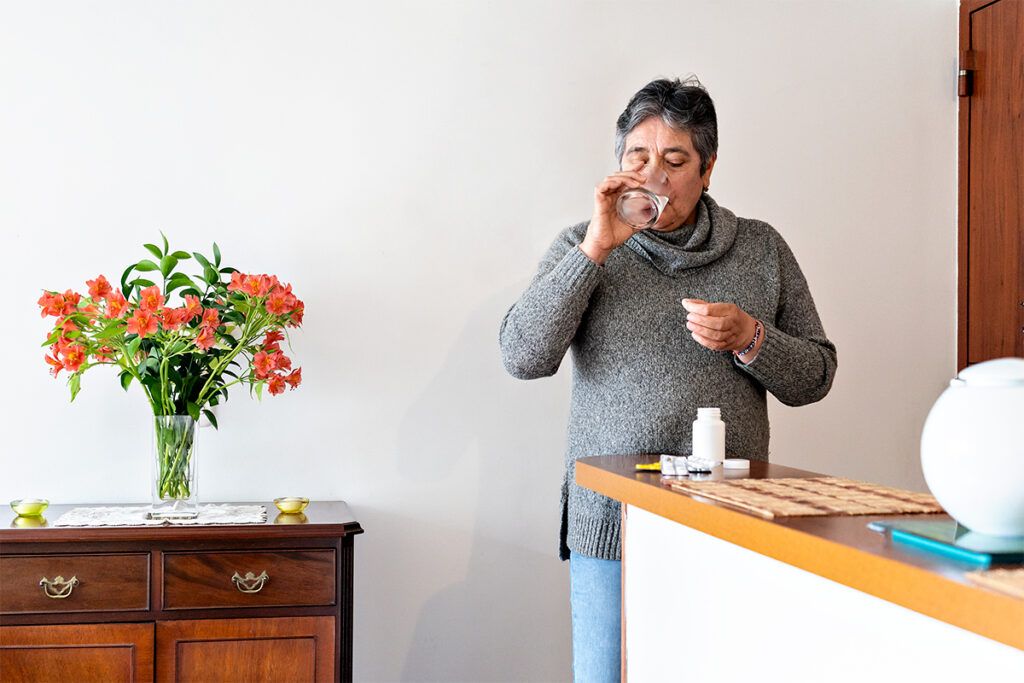 An image of a person taking pills and drinking water.