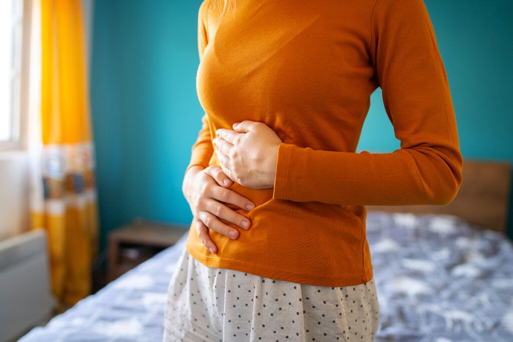 A person in an orange jumper holding their belly