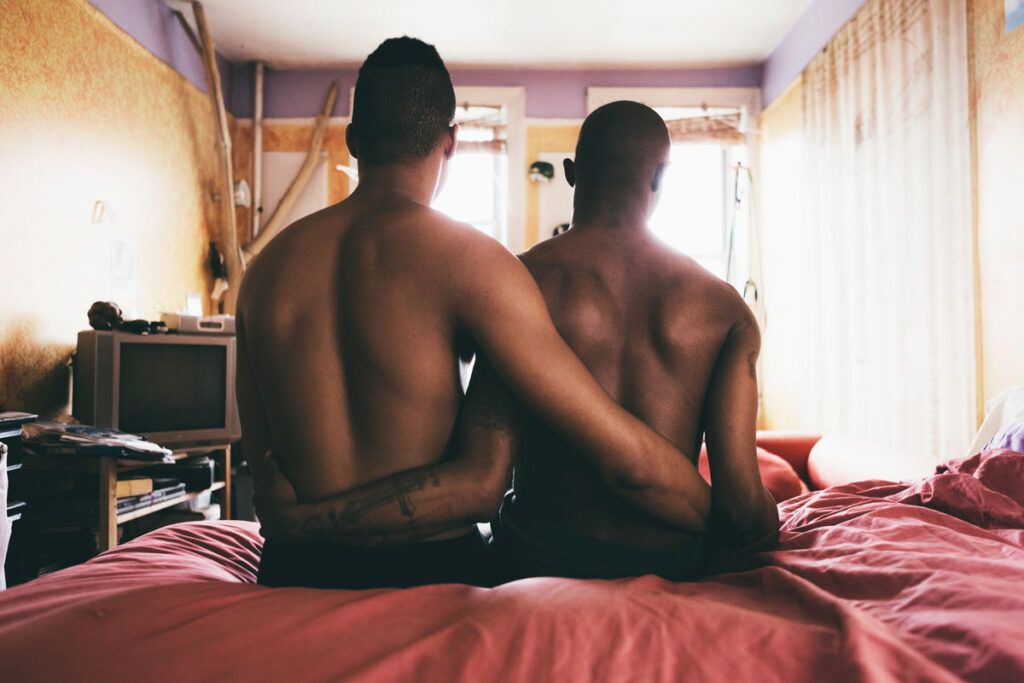 Two people sitting on a bed with their arms around each other.
