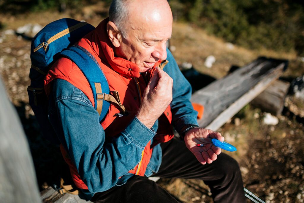An older adult taking medication while on a hike