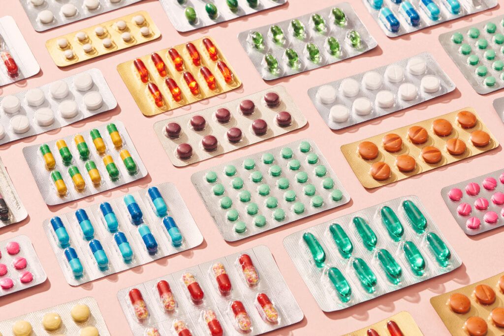 Fourteen pill packets containing different colored pills arranged in a grid