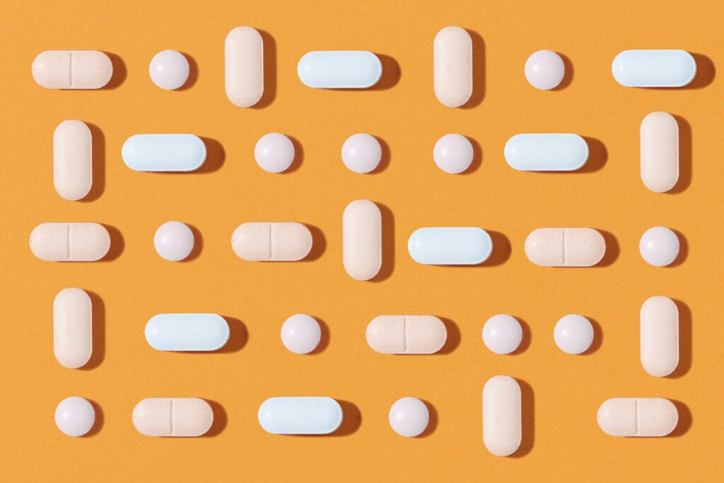 White pills laid out in a grid on an orange background