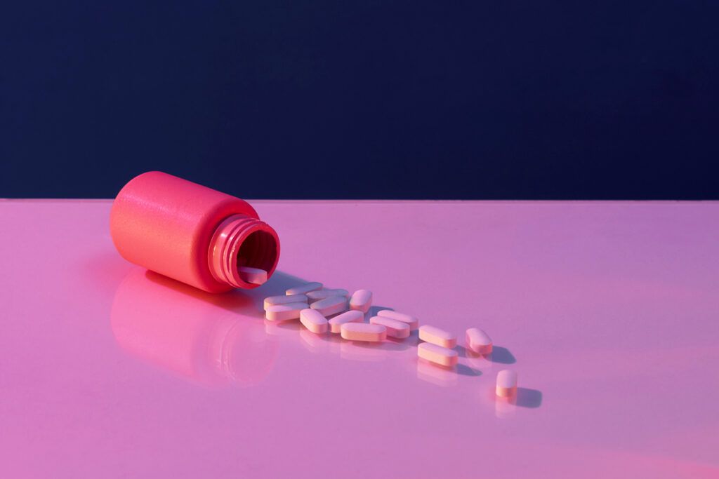 An open pill bottle on its side, spilling pills onto a surface.