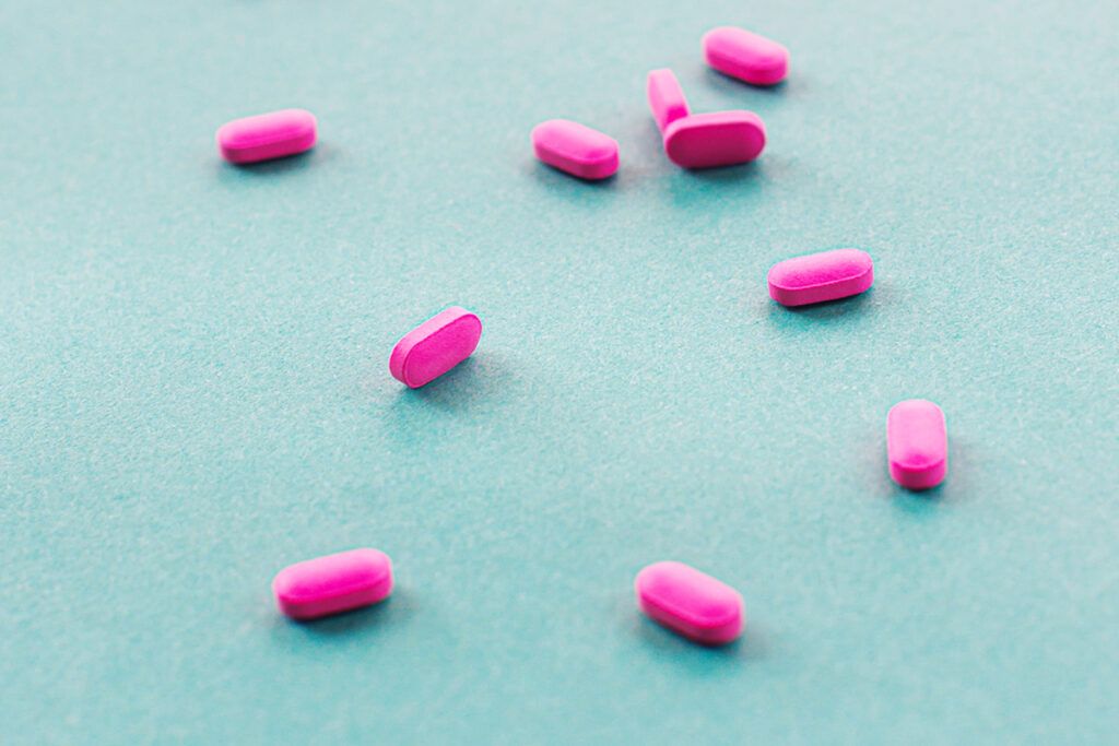 Pink pills scattered on a blue background