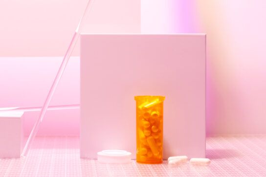 An orange bottle of pills against a pink background