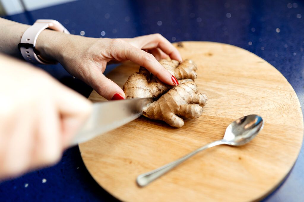 A person slicing a fresh ginger root