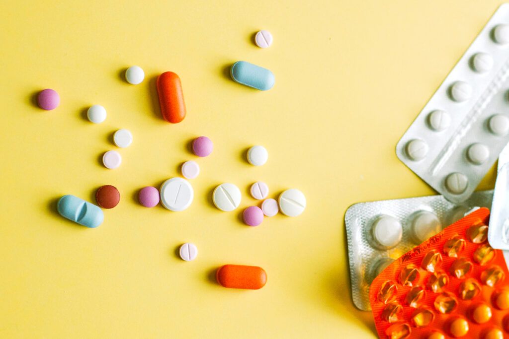 Various pills and tablets scattered on a yellow background
