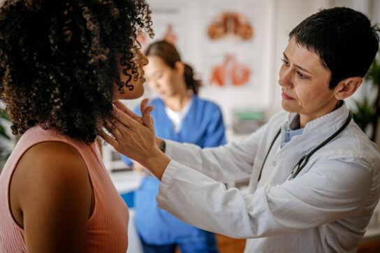 Doctor examining thyroid or lymph glands in patient's neck