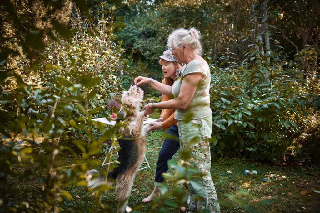 An older woman and a younger woman outside playing with a dog.