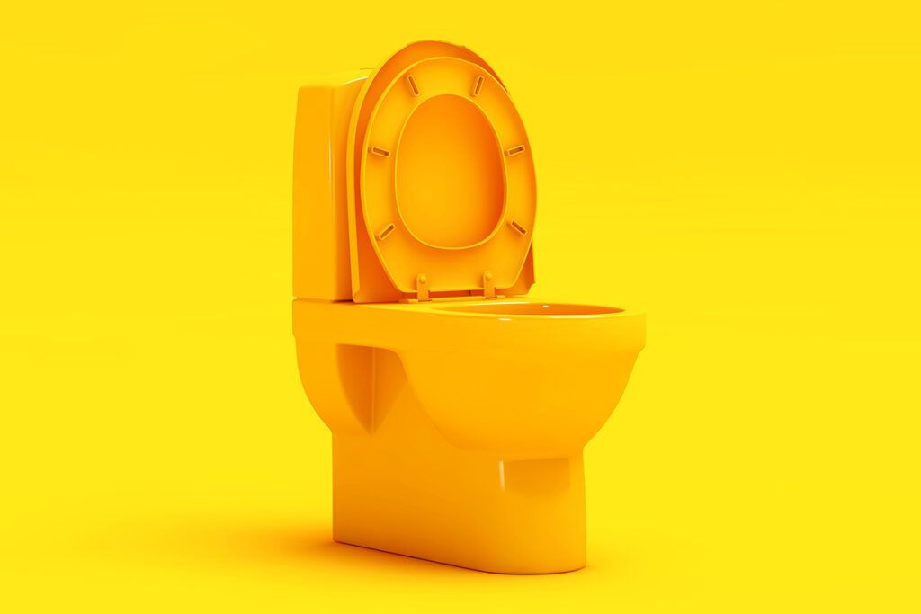 An orange toilet in front of a yellow background