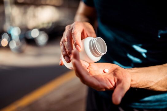 Close up of a person's hands emptying a pill into their palm from a pill bottle as they wonder what is the best time to take blood pressure medicine