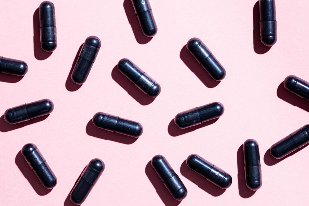 A scattering of activated charcoal capsules depicting activated charcoal benefits 