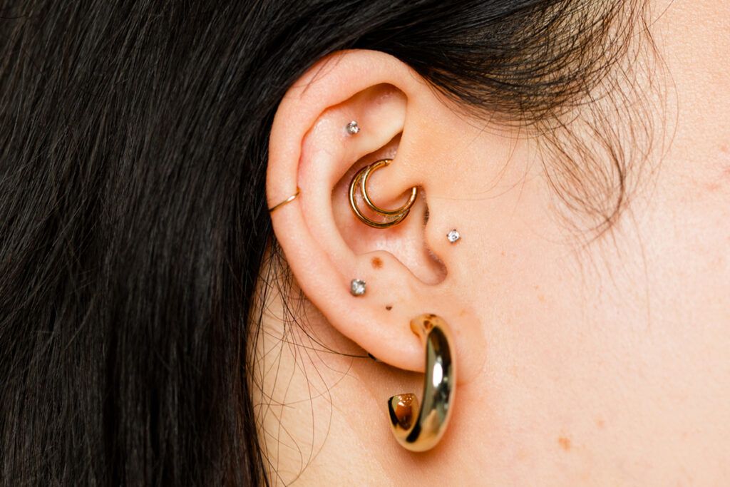 An image of someone's right ear that has several piercings.