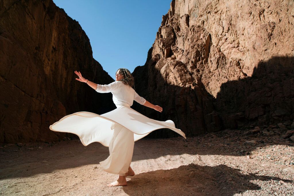 Female dancing outdoors, barefoot, and in a white dress.
