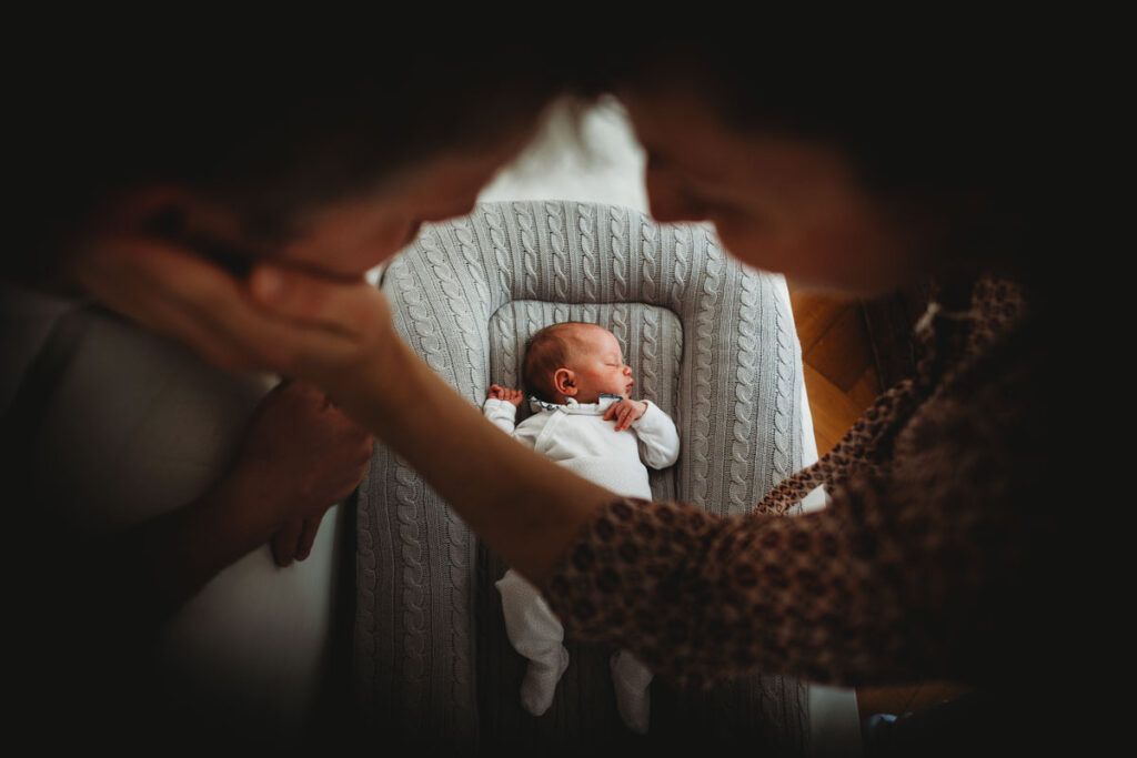 Two parents looking over a young baby