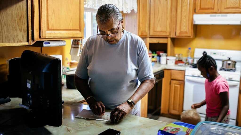 Older adult experiencing stress and high cholesterol levels fixes prescription pills in the kitchen