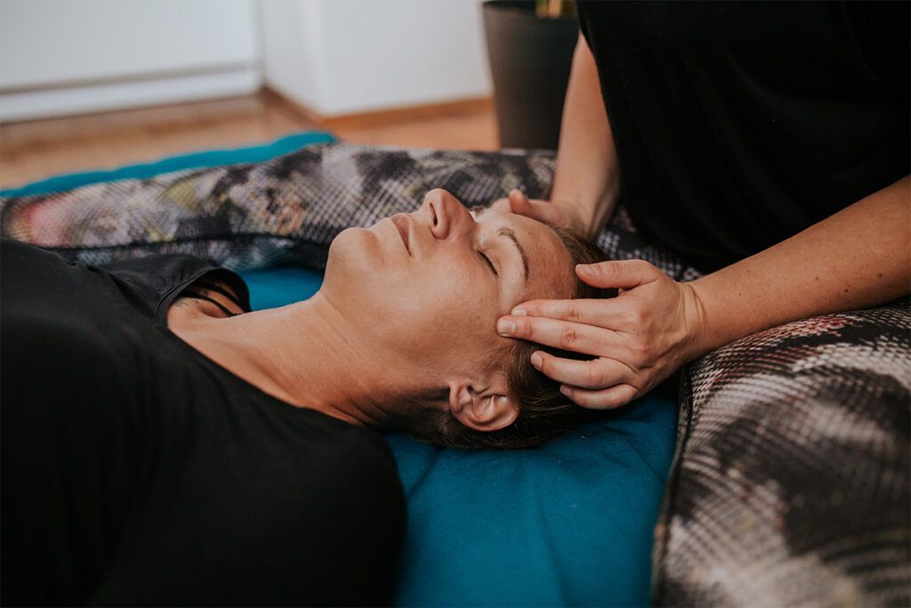 Female laying down whilst someone massages her temples. 