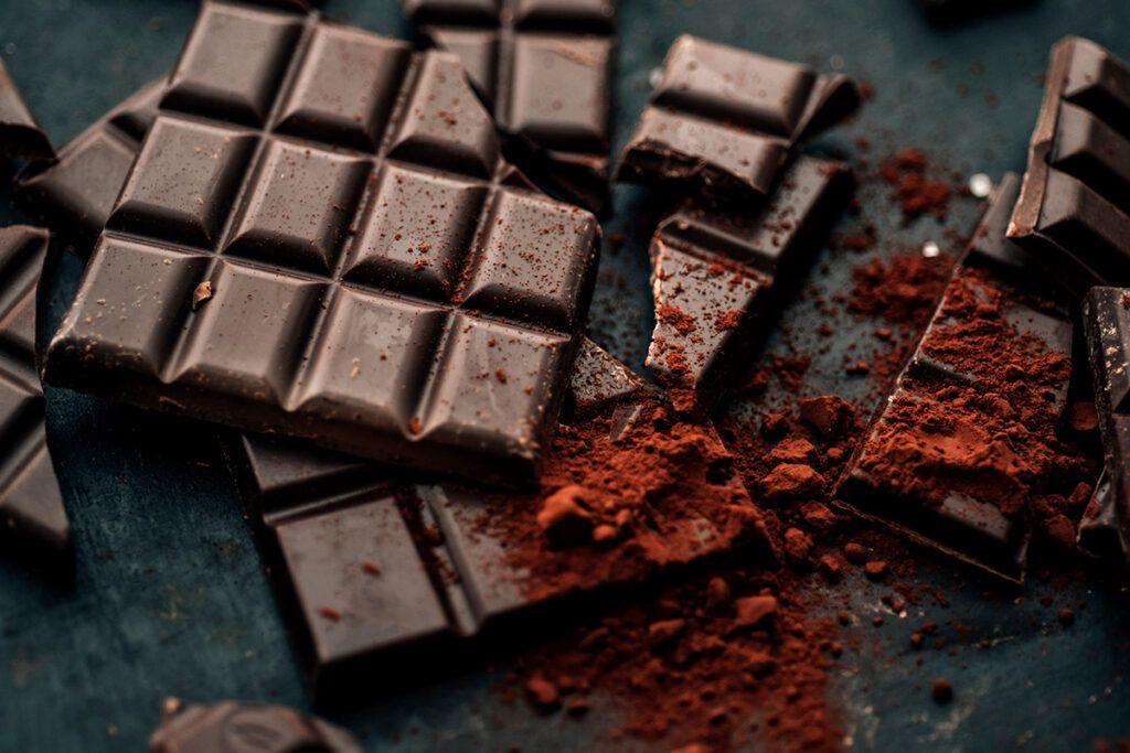Several broken bars of dark chocolate with chilli powder on top of it.
