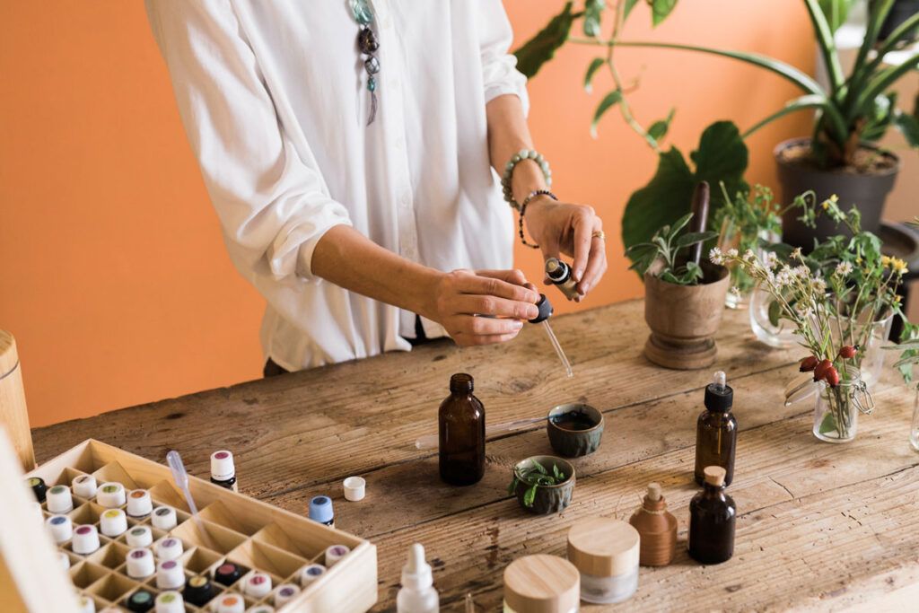 A person adding drops of essential oils to a small bowl.