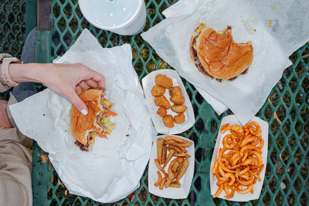 Woman eating foods to avoid for Crohn's disease like burgers and fries