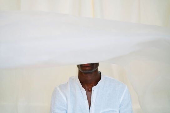 Man taking medications for social anxiety disorder hiding behind bedsheets