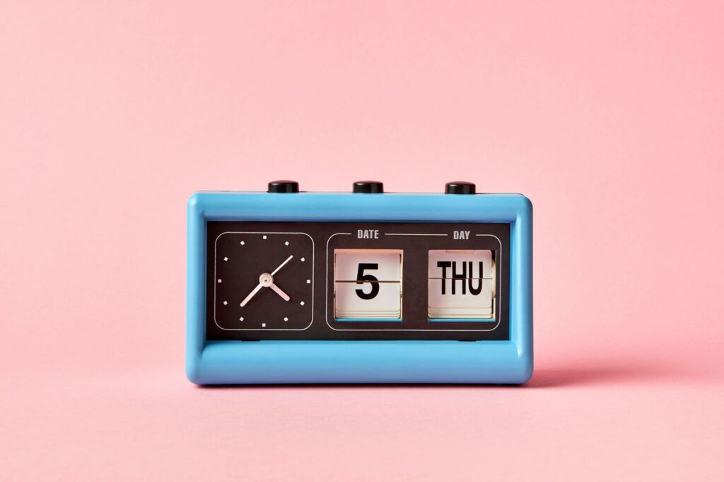 A small blue-framed rectangular analogue clock with the date and day next to it depicting Plan B