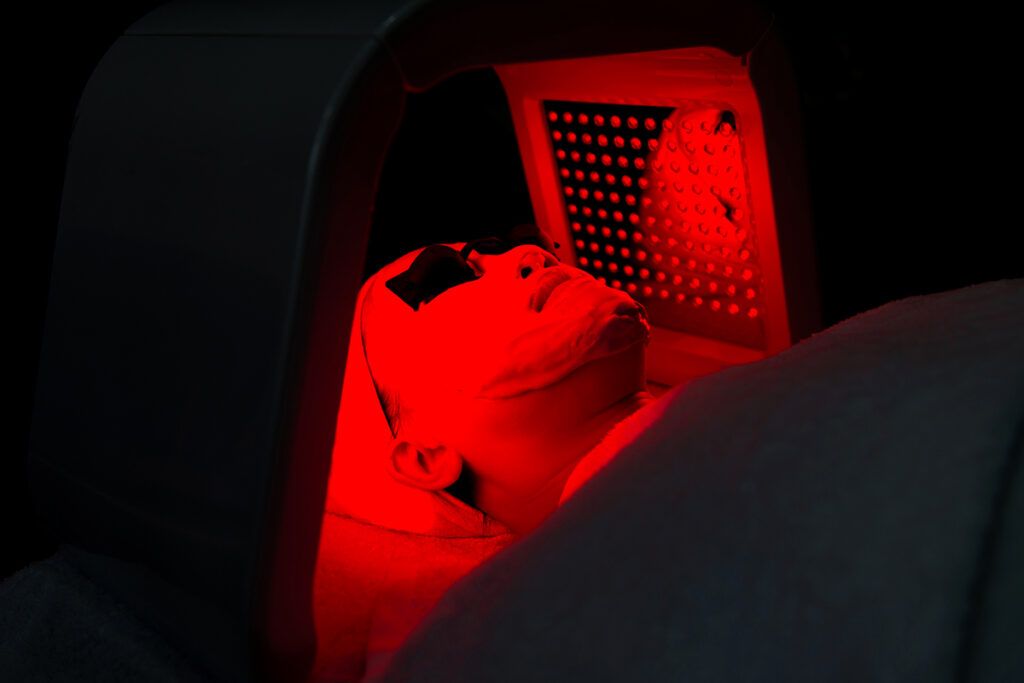 Person laying down next to a red light therapy device.